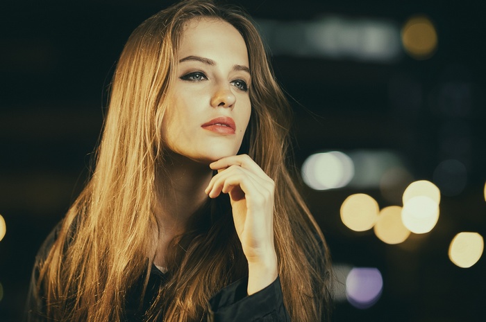 Woman with long blonde hair looking away at night