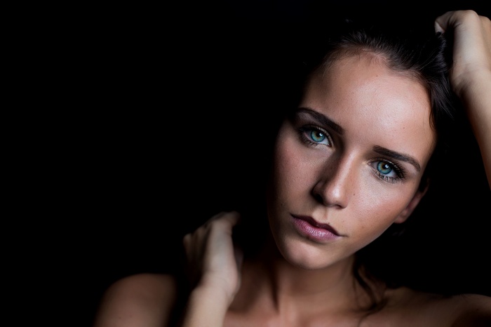 Woman with striking blue eyes against a black background
