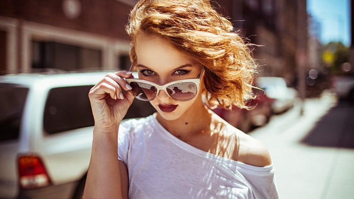 Woman with red hair and sunglasses on street