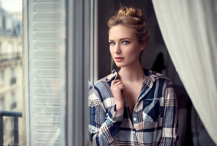 Woman in plaid shirt by the window