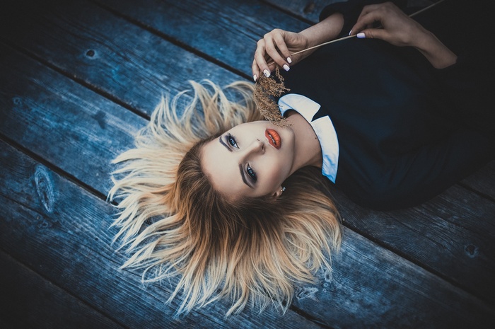 Woman with blonde hair lying on wooden surface
