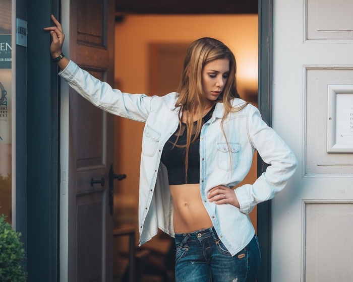Woman in denim shirt and jeans standing in doorway
