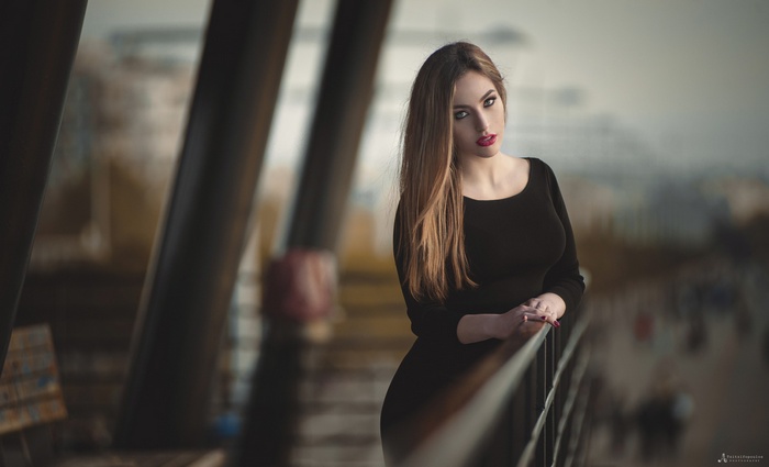 Woman with long blonde hair in a black dress on a balcony