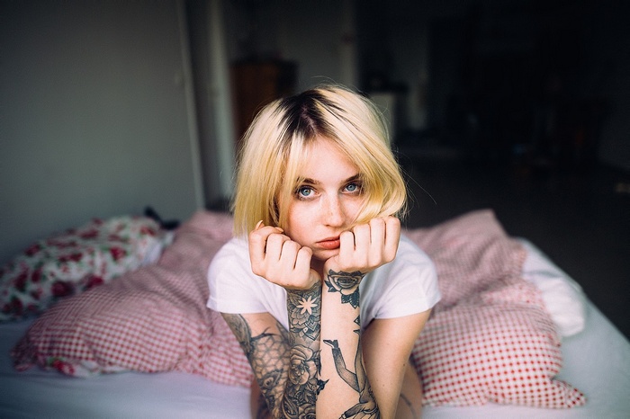 Woman with blonde hair and tattoos in bed