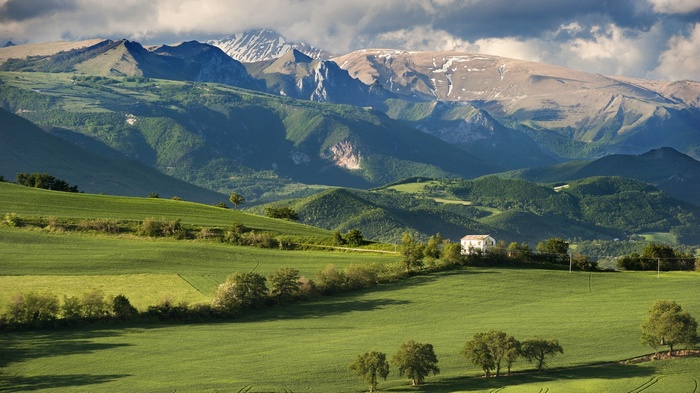 Green hills and mountains with a house and trees