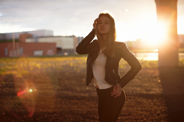 Woman with long blonde hair in a leather jacket at sunset