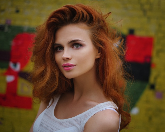 Redhead woman with striking makeup in front of abstract art