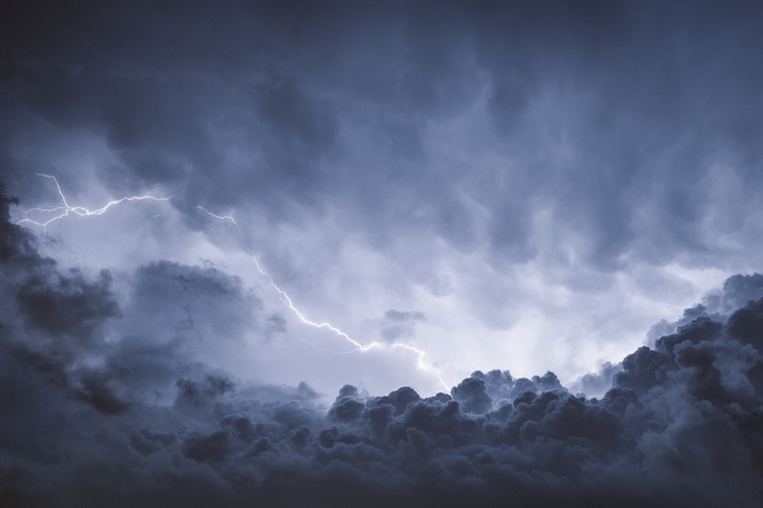 Lightning strikes through dark storm clouds in the sky