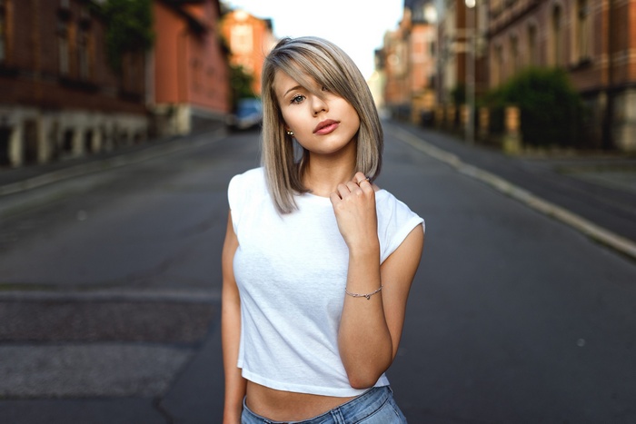 Woman in white t-shirt and denim standing on a street