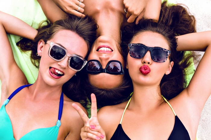 Three women in bikinis and sunglasses lying down