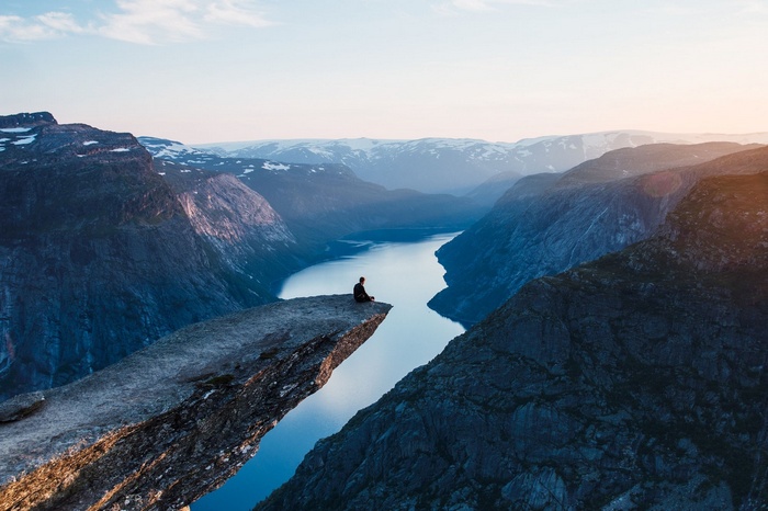 Person sitting on Trolltunga cliff overlooking a fjord in Norway