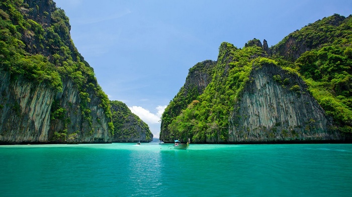 Boats in a tropical bay with limestone cliffs in Thailand