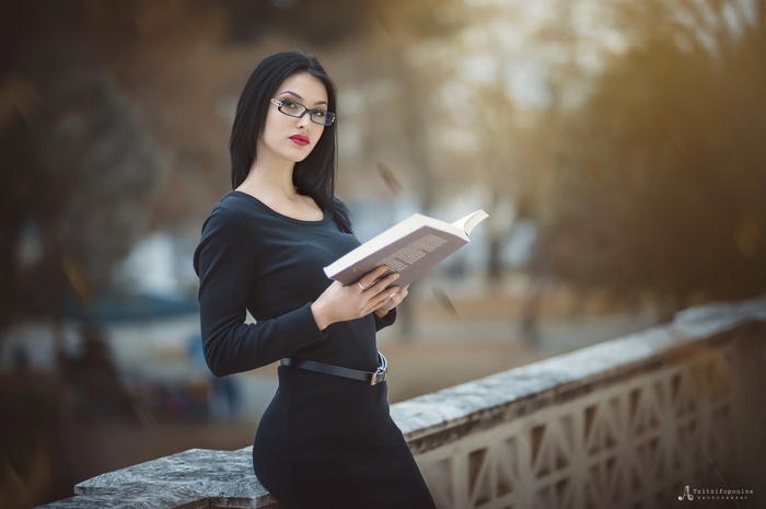 Woman with glasses reading a book outdoors