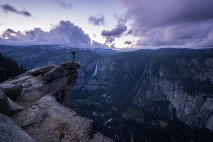 Man on cliff overlooking Yosemite Falls at dusk