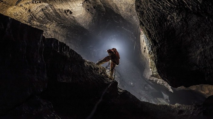 Speleologist rappelling down into Pit Olimp cave in Croatia