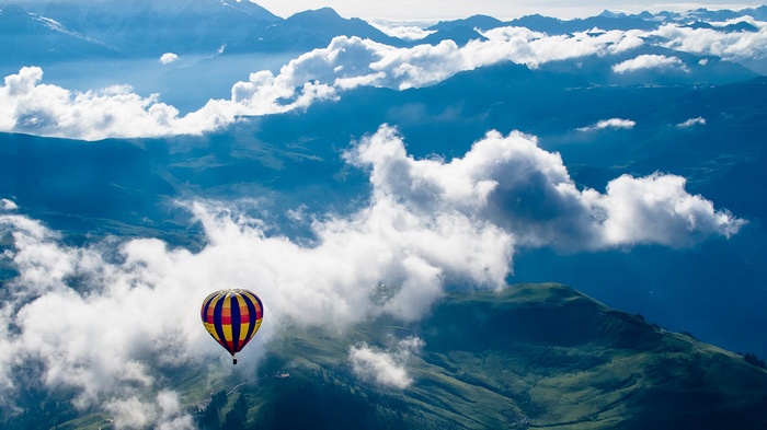 Hot air balloon over mountains and clouds