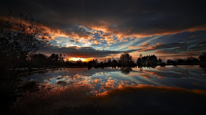 Sunset over a lake with dramatic clouds and reflections