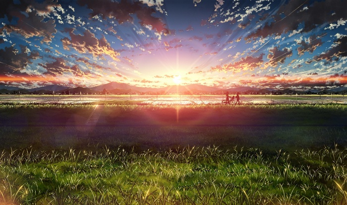Sunset over a rural landscape with two people on bicycles