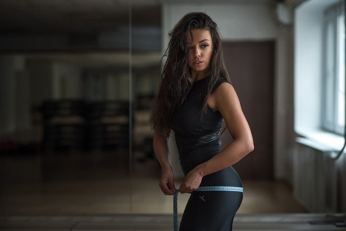 Woman in black clothing measuring her waist