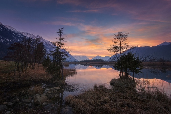 Sunset over a calm lake with mountains and trees in Germany