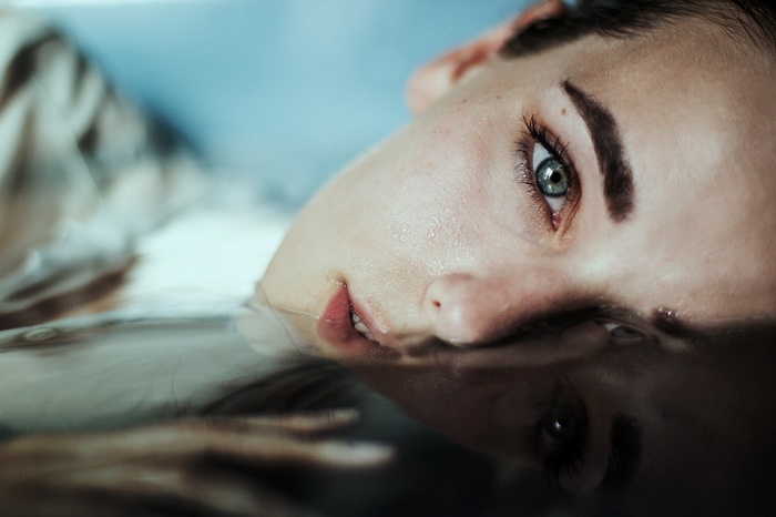 Woman's face partially submerged in water, reflection visible