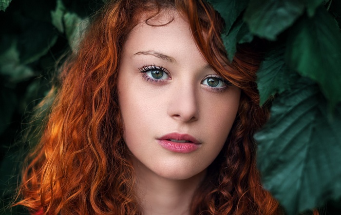 Redhead woman with green eyes surrounded by leaves