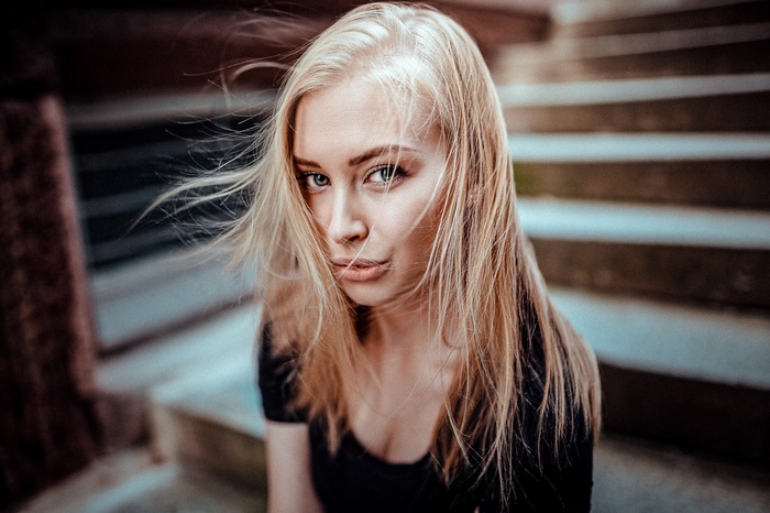 Woman with blonde hair looking at viewer on stairs