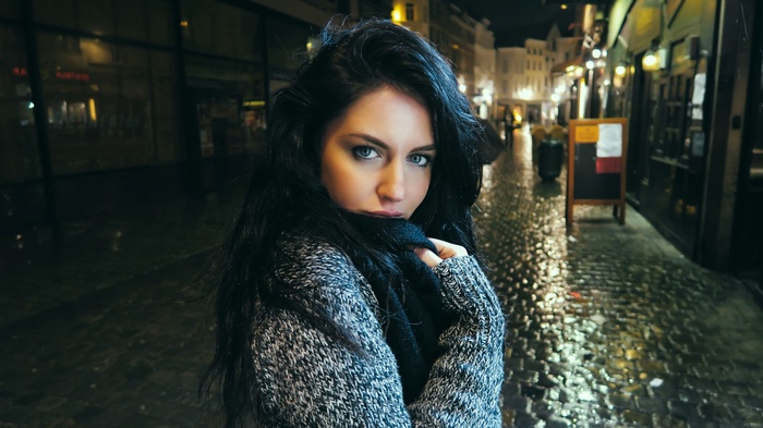 Aurela Skandaj looking at viewer on a wet city street at night