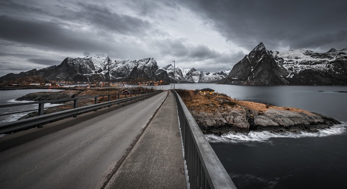 Road leading to snow-capped mountains and a village