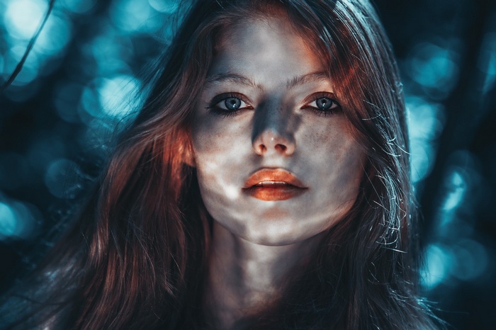 Woman with long hair and freckles looking at viewer