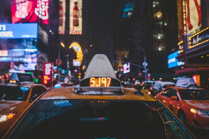 Yellow taxi with illuminated sign in Times Square at night