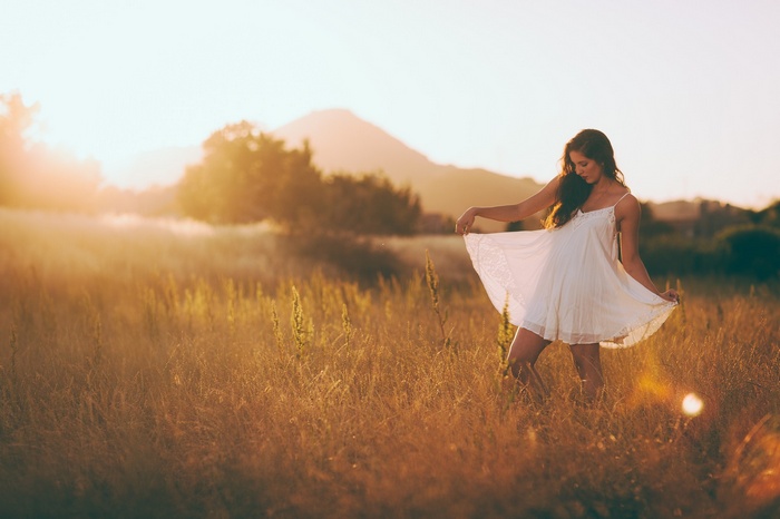 Woman in white dress in a field at sunset