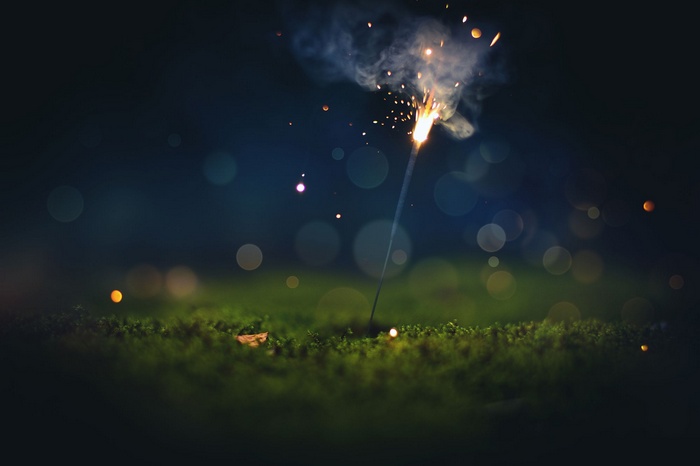 Sparkler with bokeh lights on mossy ground
