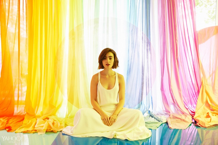 Lily Collins sits in front of a rainbow backdrop