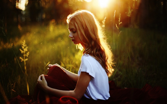 Woman sitting in a field during golden hour