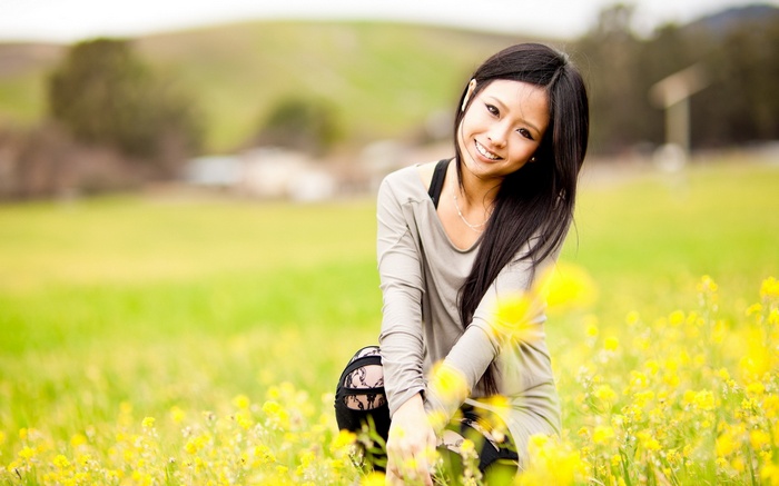 Asian woman smiling in a field of yellow flowers