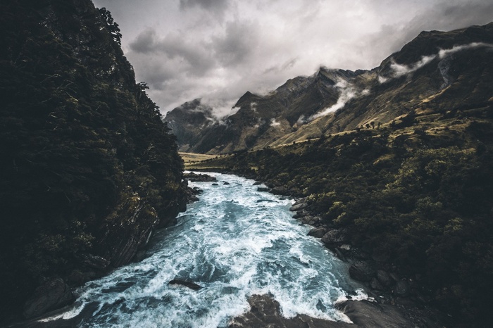 A turbulent river flows through a mountainous forest landscape
