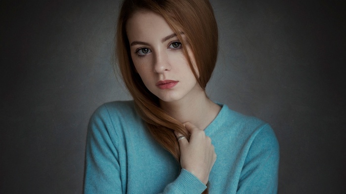 Woman with auburn hair wearing a blue sweater