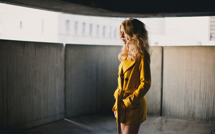 Woman with blonde curly hair in a yellow coat