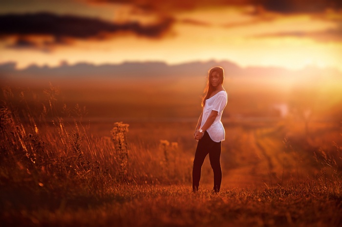 Woman standing in a field at sunset