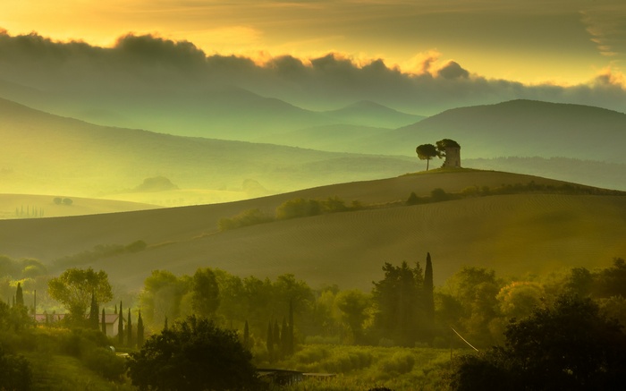 Misty Tuscan hills with cypress trees and a lone tower
