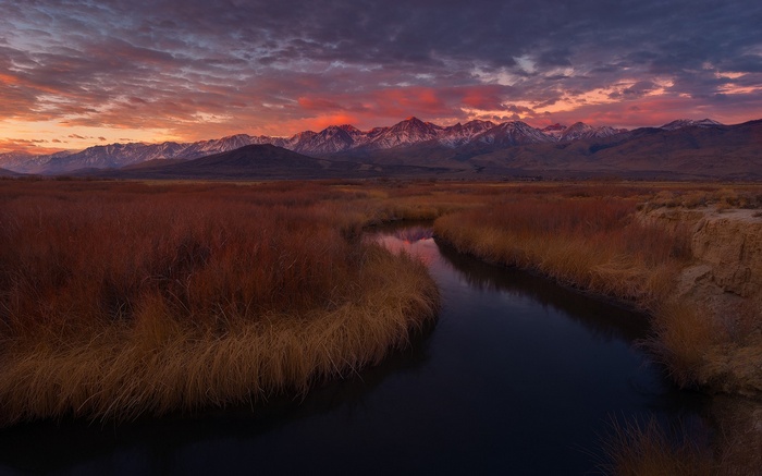 River flowing through a marsh at sunset with mountains