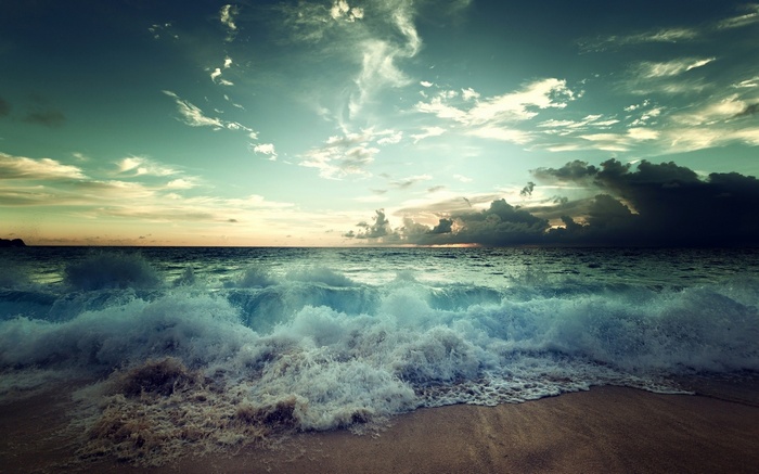 Waves crashing on a beach under a cloudy sky