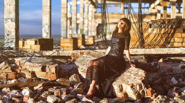 Woman in black dress sitting in ruins
