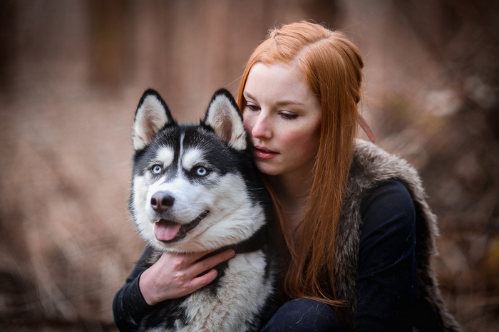Redhead woman hugging a husky dog outdoors