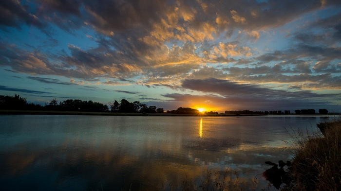 Sunset over a calm river with colorful clouds