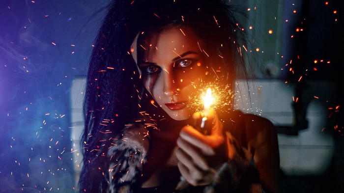 Woman holding a lit lighter with sparks flying