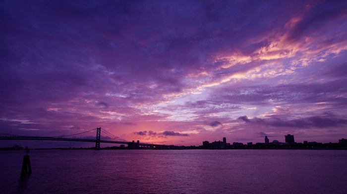 Purple sky over a bridge and city skyline