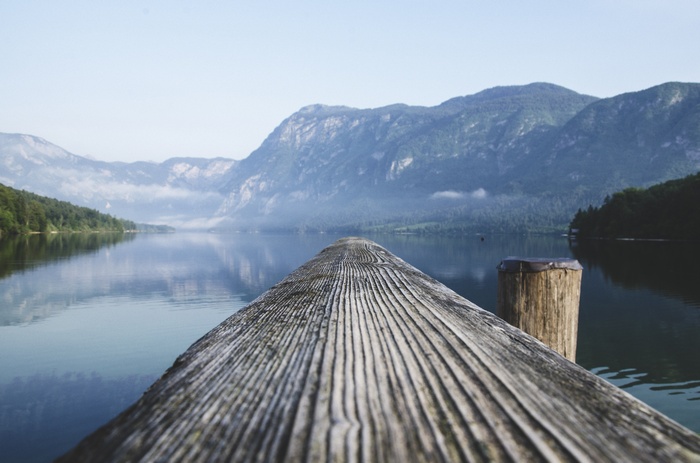 Wooden dock on a calm lake with mountains in the background