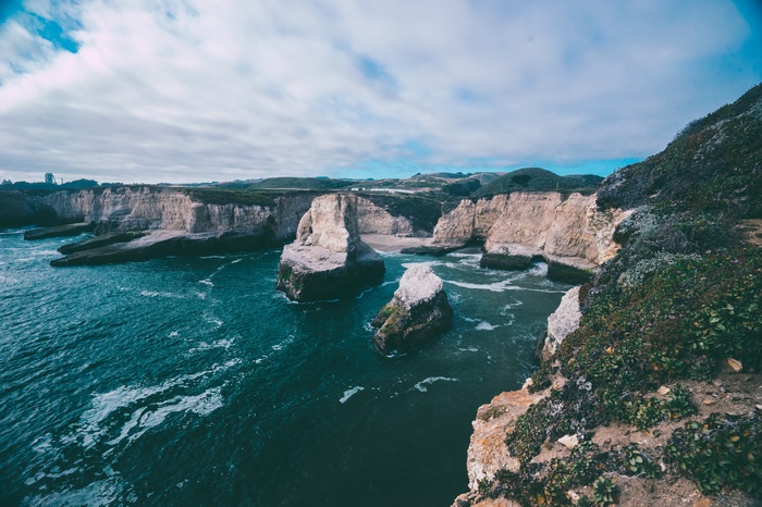Coastal cliffs and ocean waves under a cloudy sky